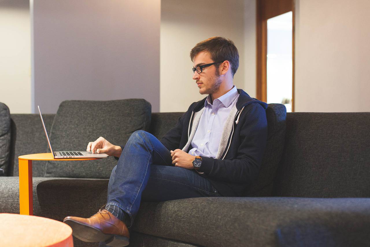 man on computer on couch