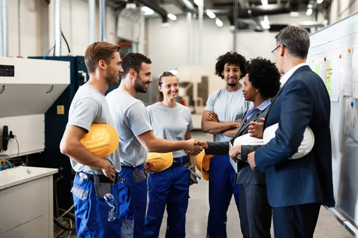 Employee Rights to Unionize and Bargain Collectively Workers shaking hands with a manager in a manufacturing setting
