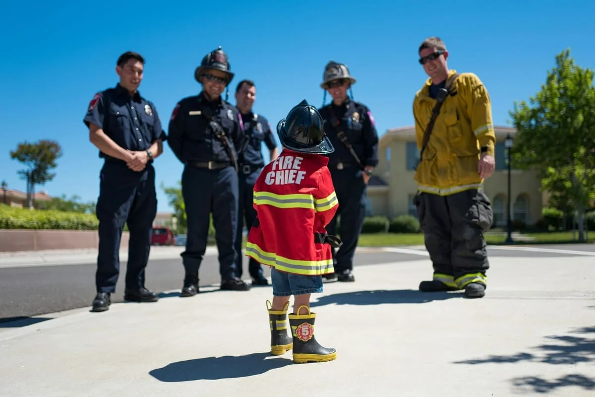 Emergency Break Policy Symbol: Firefighters with Future Fire Chief Group of firefighters standing with a child dressed as a fire chief, illustrating the unique break policies for emergency and public safety workers.