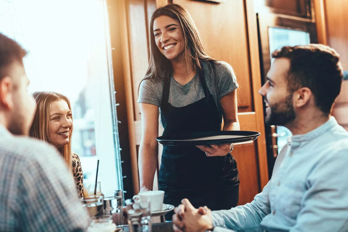 Minimum Wage Laws for Tipped Employees Smiling waitress serving customers in a café