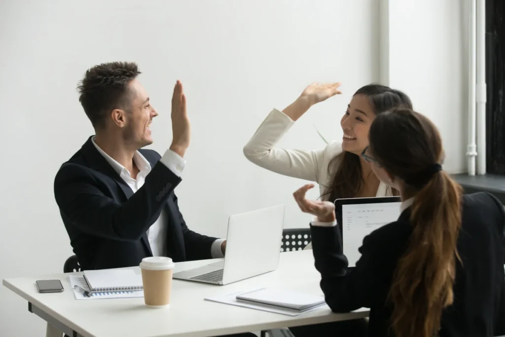employees high five each other for successfully using Time Tracking Software for Employees