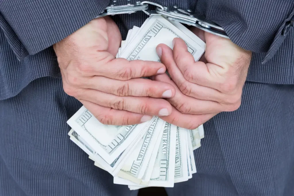 man in handcuffs while holding cash for not Clock In and Out software