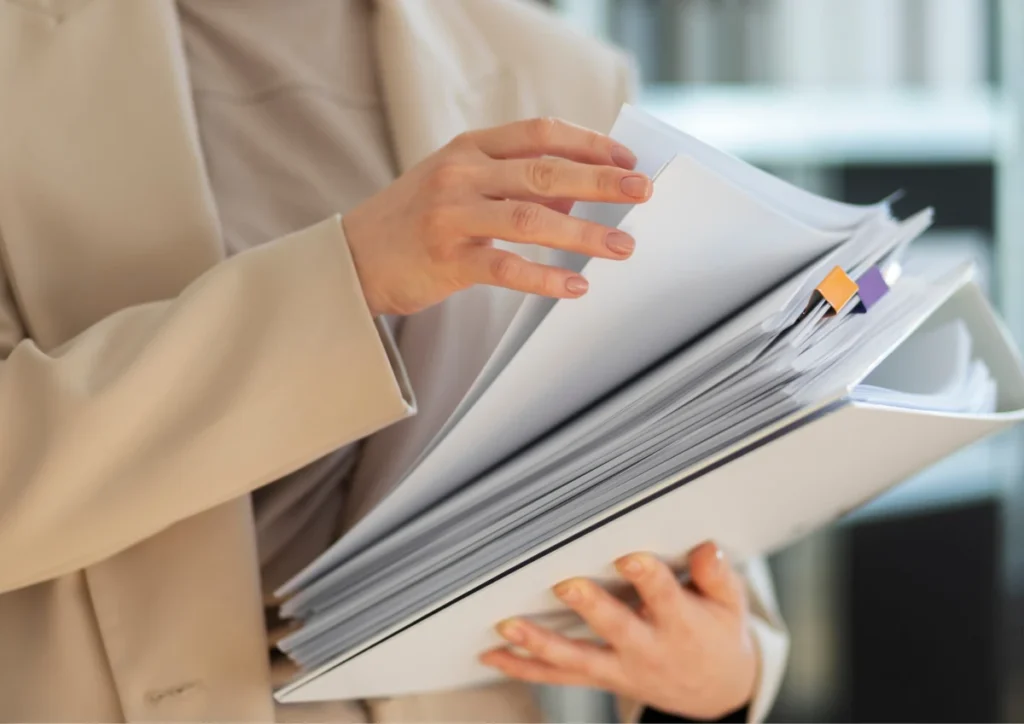 employee holding stack of papers to track work hours with Time Tracking Software