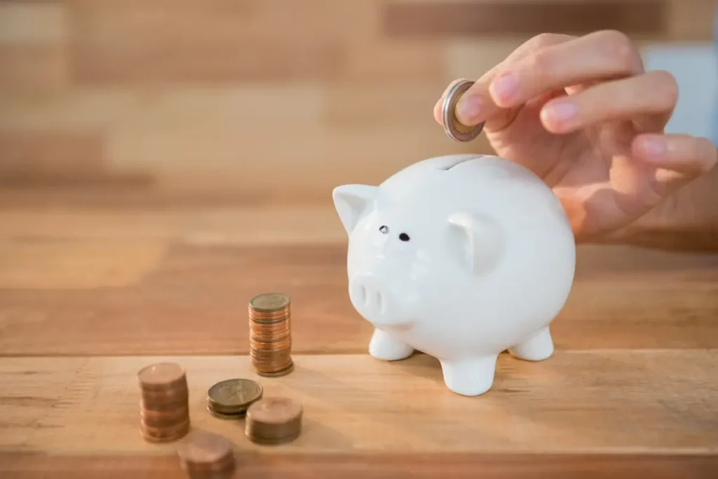 Business owner adding coins to a piggy bank to represent saving on employee time tracking software costs