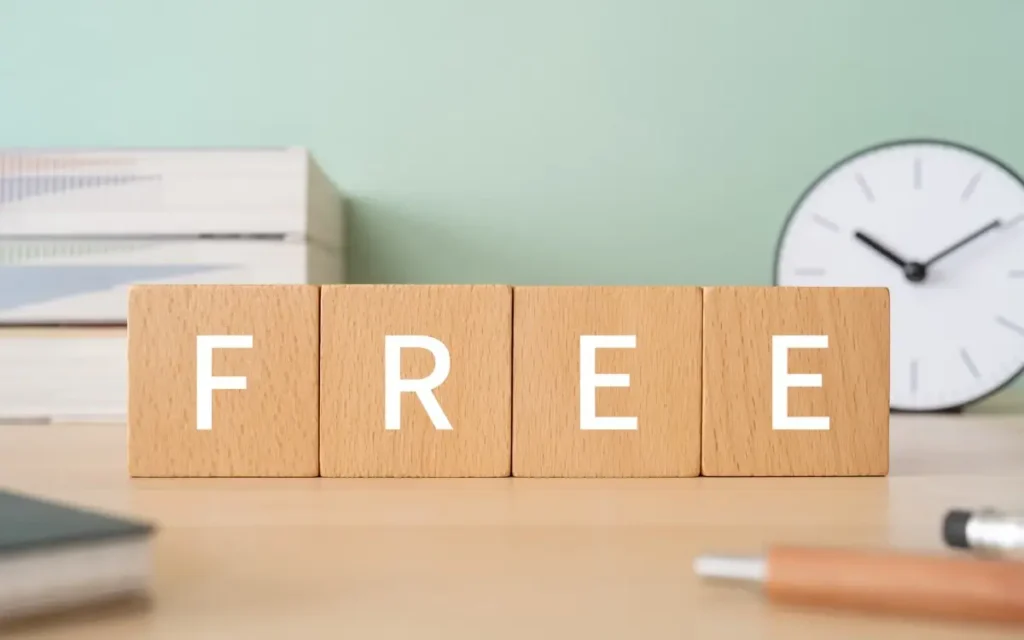 Wooden blocks spelling “free” on a desk, highlighting the limitations of free time clock software.