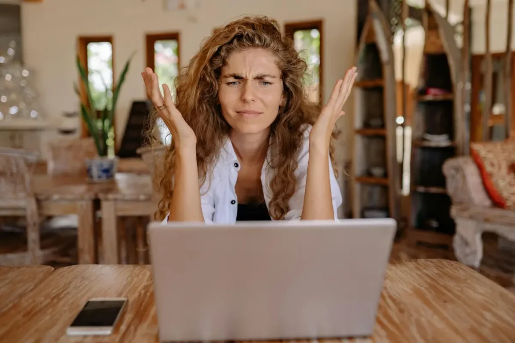 Small business owner looking frustrated while reviewing time tracking and payroll information on a laptop
