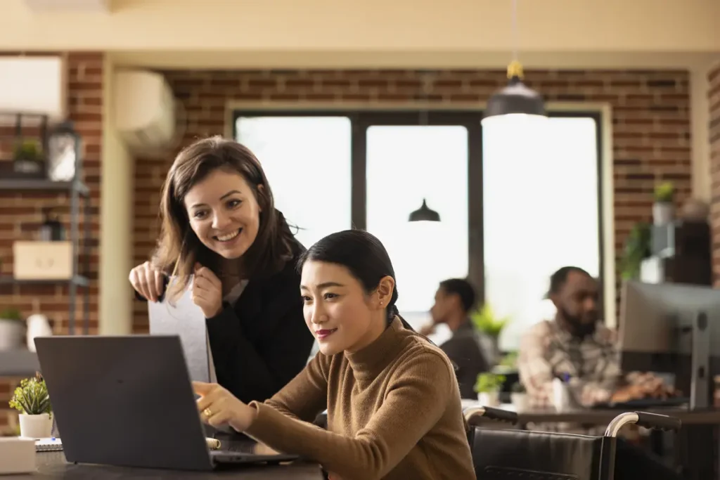 Coworkers reviewing time and payroll data together in a small business office.