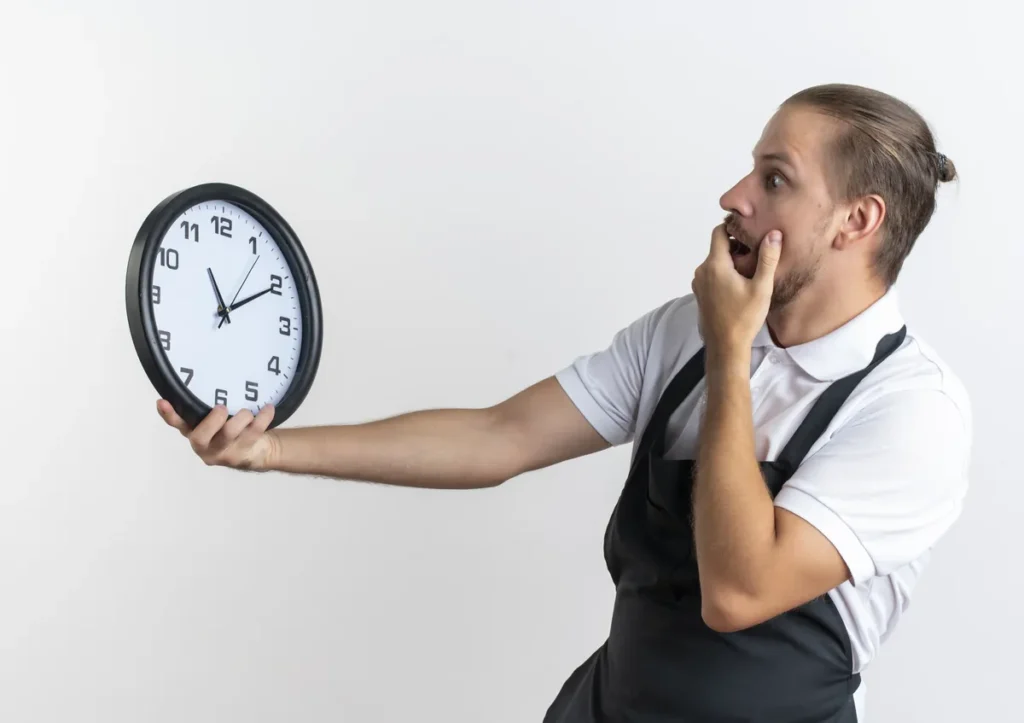 Worker holding wall clock looking surprised about time conversion from minutes to decimal hours