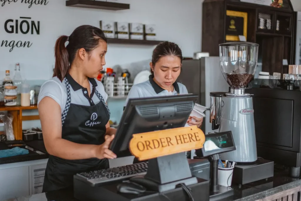 Two young employees working the order counter at a cafe