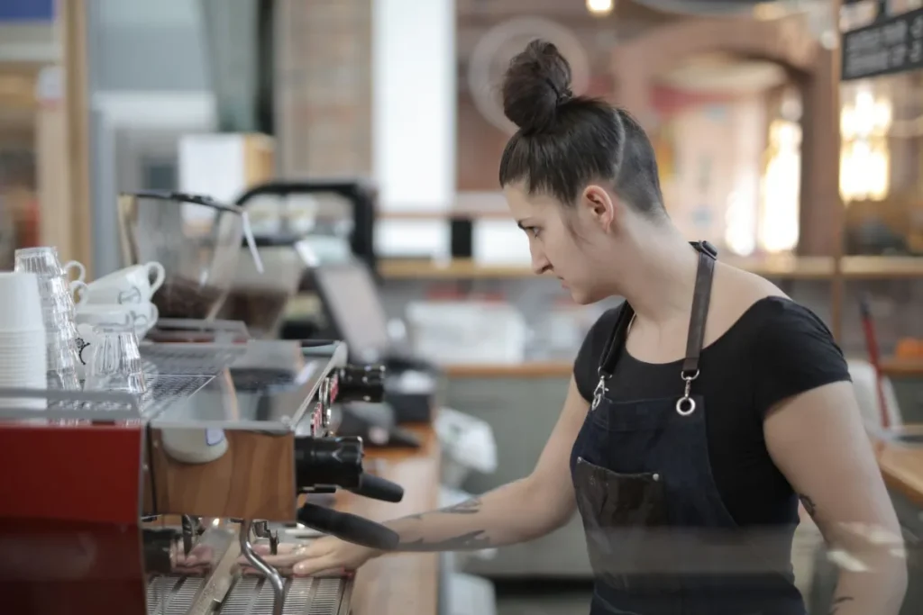 Young barista making coffee at an espresso machine