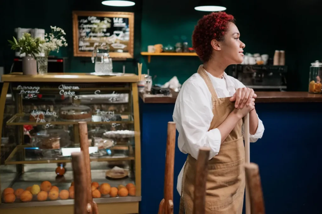 Young cafe employee in an apron behind the bakery counter